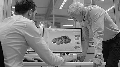 Team von Daetwyler Industries prüft Zeichnung von Maschinenbett am Arbeitsplatz.